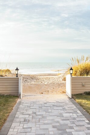 A paved pathway leading to a beach with a view of the ocean. - Carriage House Couples Retreat (Caseville)