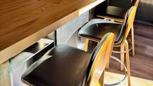 Una cocina moderna con armarios oscuros, una isla de madera y una silla negra.