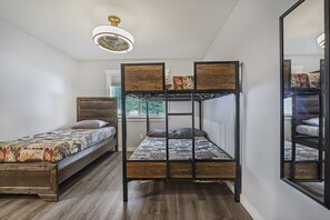 Ein Zimmer mit einem Etagenbett, einem Einzelbett und einem Spiegel.