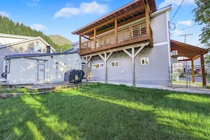 Ein zweistöckiges Haus mit einer Veranda und einem kleinen Gartenhaus.
