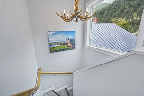 Eine Treppe mit Holzhandläufen, ein an der Wand befestigtes Landschaftsbild und eine Chandelüster.
