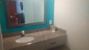 A bathroom with a granite countertop, a sink, and a mirror.
