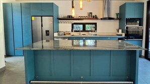 Una cocina moderna con armarios color turquesa, encimera de mármol e iluminación colgante.