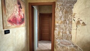A hallway with a stone wall, a wooden door, and a framed painting on the wall. - "Stylish and modern stay a stone's throw from downtown close to all amenities" (Modena)