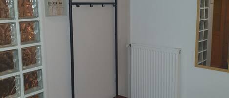 A room with a metal rack, a radiator, and patterned floor.