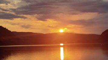 A sunset over a calm lake with a distant mountain range.
