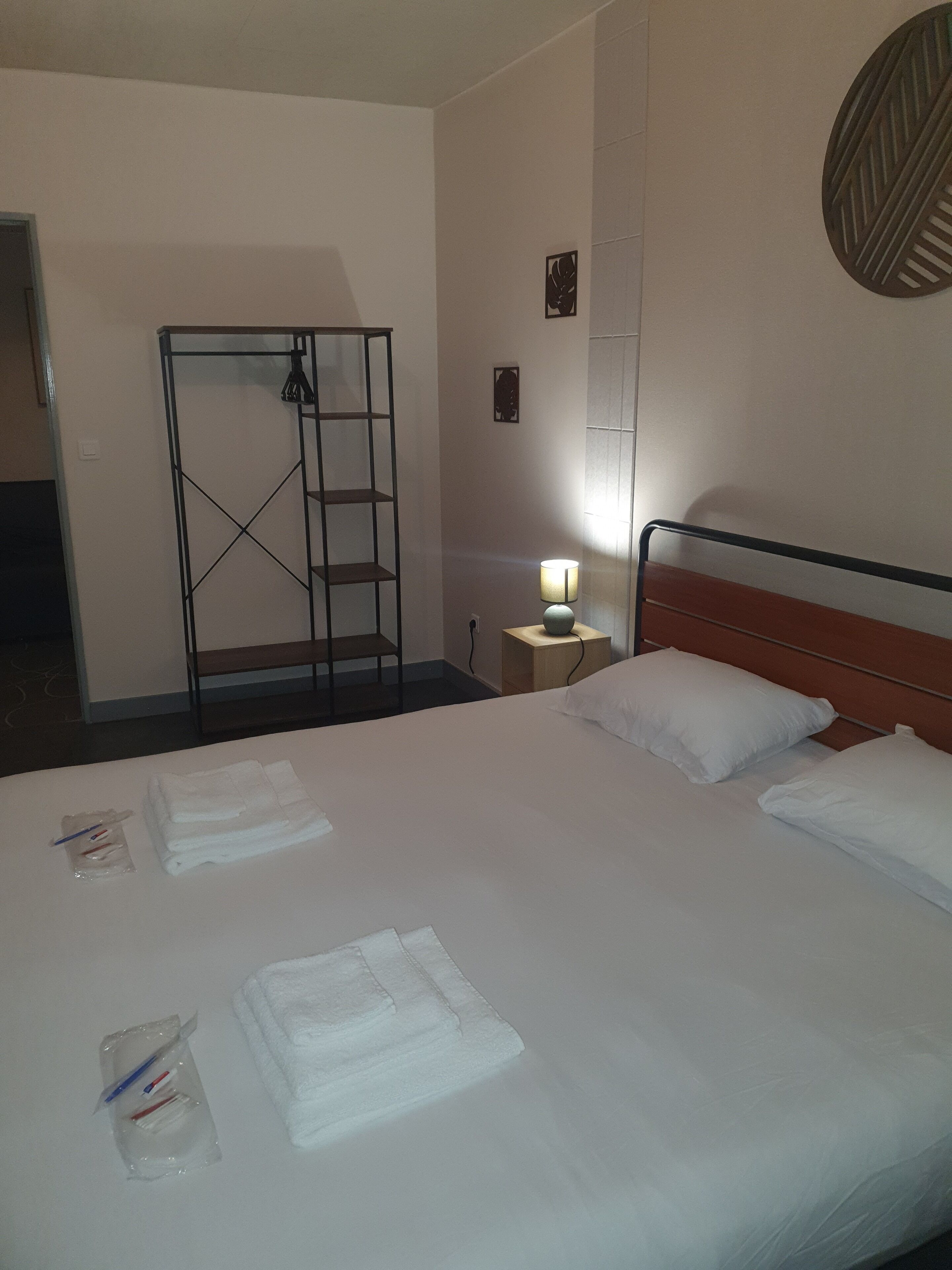 Ein Hotelzimmer mit einem großen Bett, einem Nachttisch mit Lampe, einem Kleiderschrank und einer kleinen Wanddekoration.