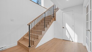 Una escalera con escalones de madera y barandales de metal, una puerta blanca y vista al cielo.