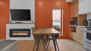 A modern kitchen with a fireplace, dining table, and built-in appliances. - Apartment 103 | NEW | Downtown (Rimouski)