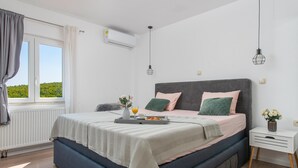 Een slaapkamer met een bed, nachtkastje en een raam met gordijnen.