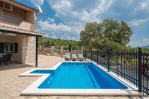 A swimming pool with lounge chairs, a stone wall, and a satellite dish. - Peaceful Holiday Villa in Kladnjice (Lećevica)