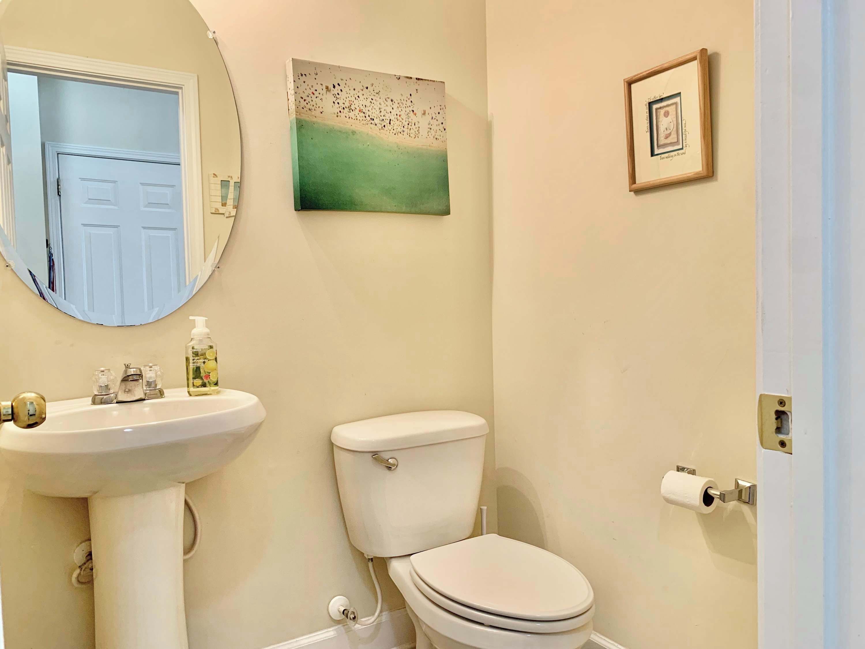 Een badkamer met een wastafel, toilet en een lijst met een afbeelding aan de muur.