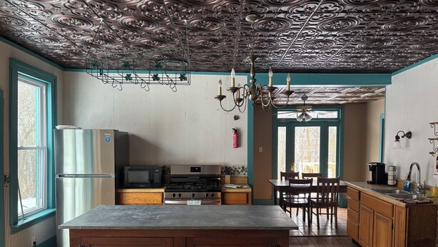 A kitchen with a central island, wooden cabinets, a stove, and a microwave. - Victorian home built in 1834. (Union City)