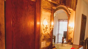 A bathroom with a wooden door, a large mirror, and a sink with a red towel. - Moonshine Runners Cabin (Tracy City)