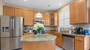 Una cocina moderna con armarios de madera, electrodomésticos de acero inoxidable, encimeras de granito y una isla central.
