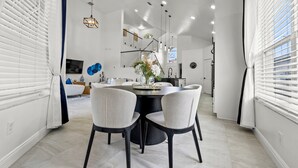 A modern dining area with a round table, two chairs, and a vase with flowers. - Spacious 5-bedroom house, mins from Disney World & major attractions (Kissimmee)