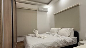 Una habitación de hotel moderna con una cama, una mesita de noche, un aire acondicionado integrado y una lámpara de techo.