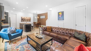 Un salon moderne avec un canapé en cuir marron, un fauteuil bleu et une table basse en bois.