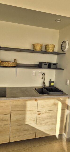 A modern kitchen with a built-in sink, wooden cabinets, and two baskets on the upper shelf.