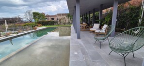 Una piscina con sillas de descanso y un patio cubierto.