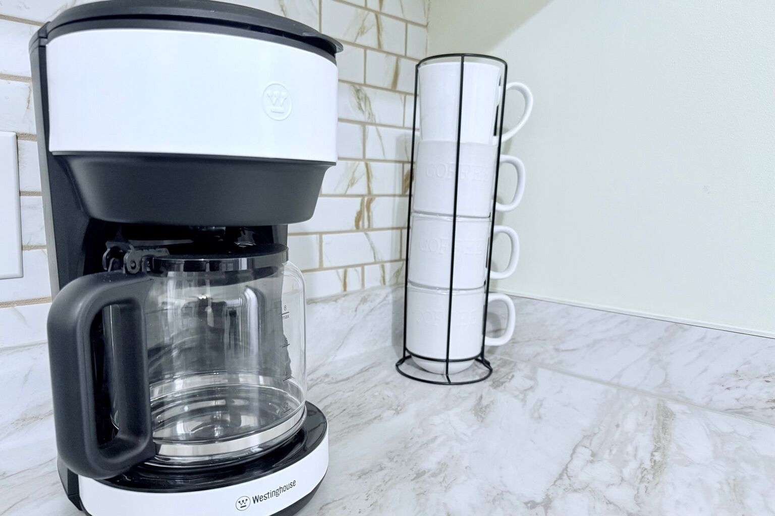 Una cafetera Westinghouse con jarra transparente y espacio para tazas.