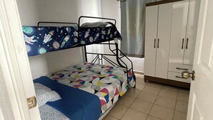 A dormitory room with bunk beds, a wardrobe, and a curtain.