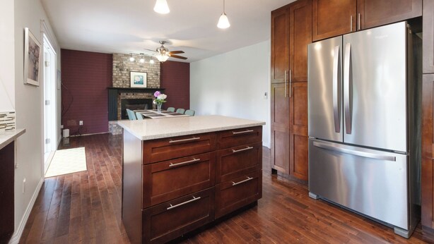 A modern kitchen with wooden cabinets, a stainless steel refrigerator, and a central island with drawers. - Surrey Family Home w/ Patio & Garden – 3BR 2BA (Surrey)
