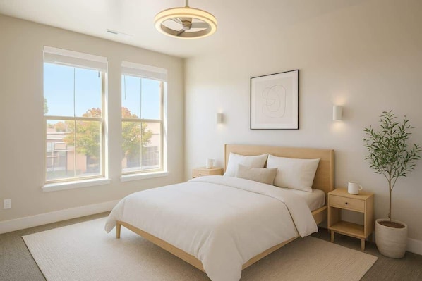 A bedroom with a bed, two bedside tables, a nightstand, a potted plant, and a framed picture on the wall.