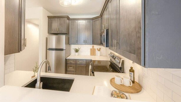 A modern kitchen with stainless steel appliances, a wooden countertop, and a built-in oven. - Grand Suite – New Construction Beauty! Pets too! (Pleasant Grove)