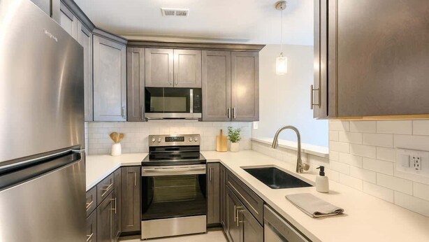 Una cocina moderna con electrodomésticos de acero inoxidable, un microondas y un lavamanos.