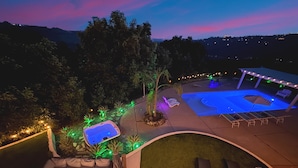 Uma área de piscina externa com banheira de hidromassagem, espreguiçadeiras e lareira.