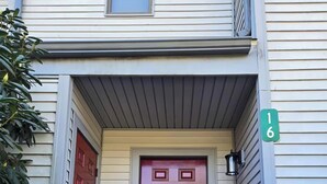 A two-story building with a red door, a green house number sign, and a small window above the door. - Fully Renovated Mountain House with a Private Spa (Lake Harmony)