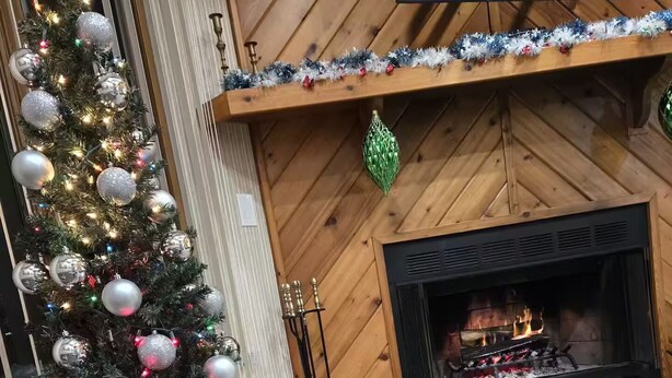 A cozy living room with a large Christmas tree, a fireplace, and a television mounted on the wall. - Fully Renovated Mountain House with a Private Spa (Lake Harmony)