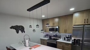 A modern kitchen with a central island, stainless steel appliances, and pendant lighting. - Fully Renovated Mountain House with a Private Spa (Lake Harmony)