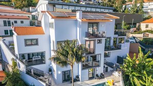Un moderno edificio residenziale a più piani con piscina sul tetto e pannelli solari.