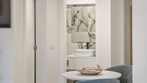 Uma casa de banho moderna com uma sanita branca, um espelho e uma tigela decorativa sobre uma pequena mesa.