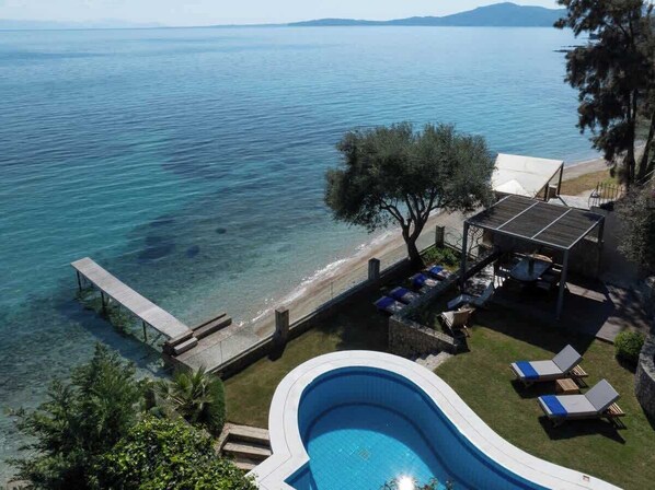 Ein Pool mit Meerblick, eine Sonnenterrasse und Liegestühle.