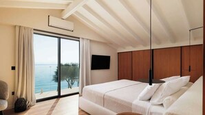 A bedroom with a large window, a bed, a TV, and a wooden ceiling. - Villa Alia, Modern Comfort Direct Beach Access (Corfu)