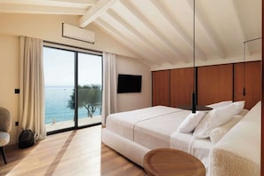 Ein Schlafzimmer mit großem Fenster, einem Bett, einem Fernseher und einer Holzzieldecke.