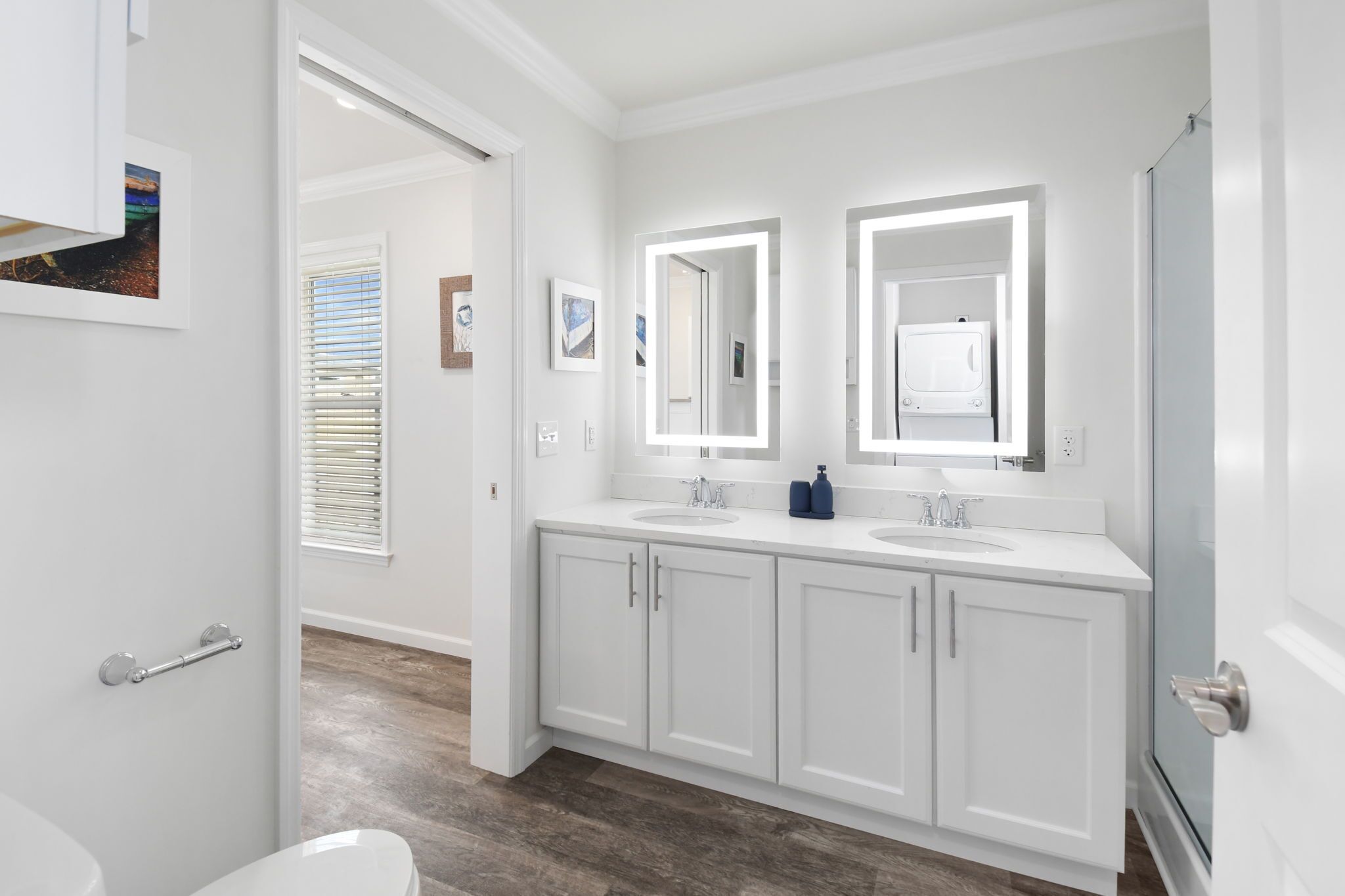 Une salle de bain moderne avec des meubles blancs, deux lavabos et un grand miroir.