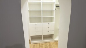Un armario espacioso con varias estanterías y cajones, suelo de madera y un arco blanco.