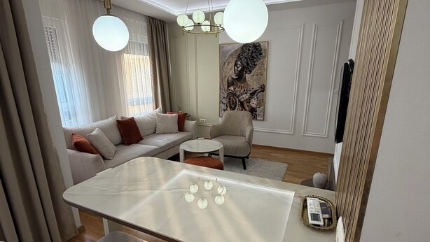 Ein modernes Wohnzimmer mit einem Glastisch, weißen Sofas und einem großen Spiegel.