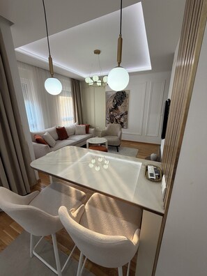 Un salón moderno con una mesa de centro de vidrio, sofás blancos y un espejo grande.