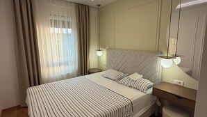 Ein modernes Schlafzimmer mit einem großen Bett, Nachttischlampen, einem Spiegel und einem Holzboden.