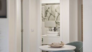 A modern bathroom with a white sink, a mirror, and a decorative bowl on a small table. - Camacho Studios - Turquoise Room by Homie (Funchal)