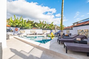 A pool area with lounge chairs, a lifeguard stand, and a view of the surrounding landscape.