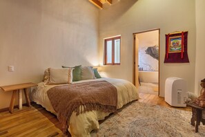 A bedroom with a bed, bedside table, window, and a wall-mounted heater. - A hidden pearl in the middle of the city (Ciudad de México)