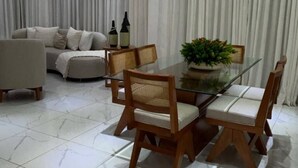 Un comedor con una mesa de vidrio, sillas de madera y una araña.