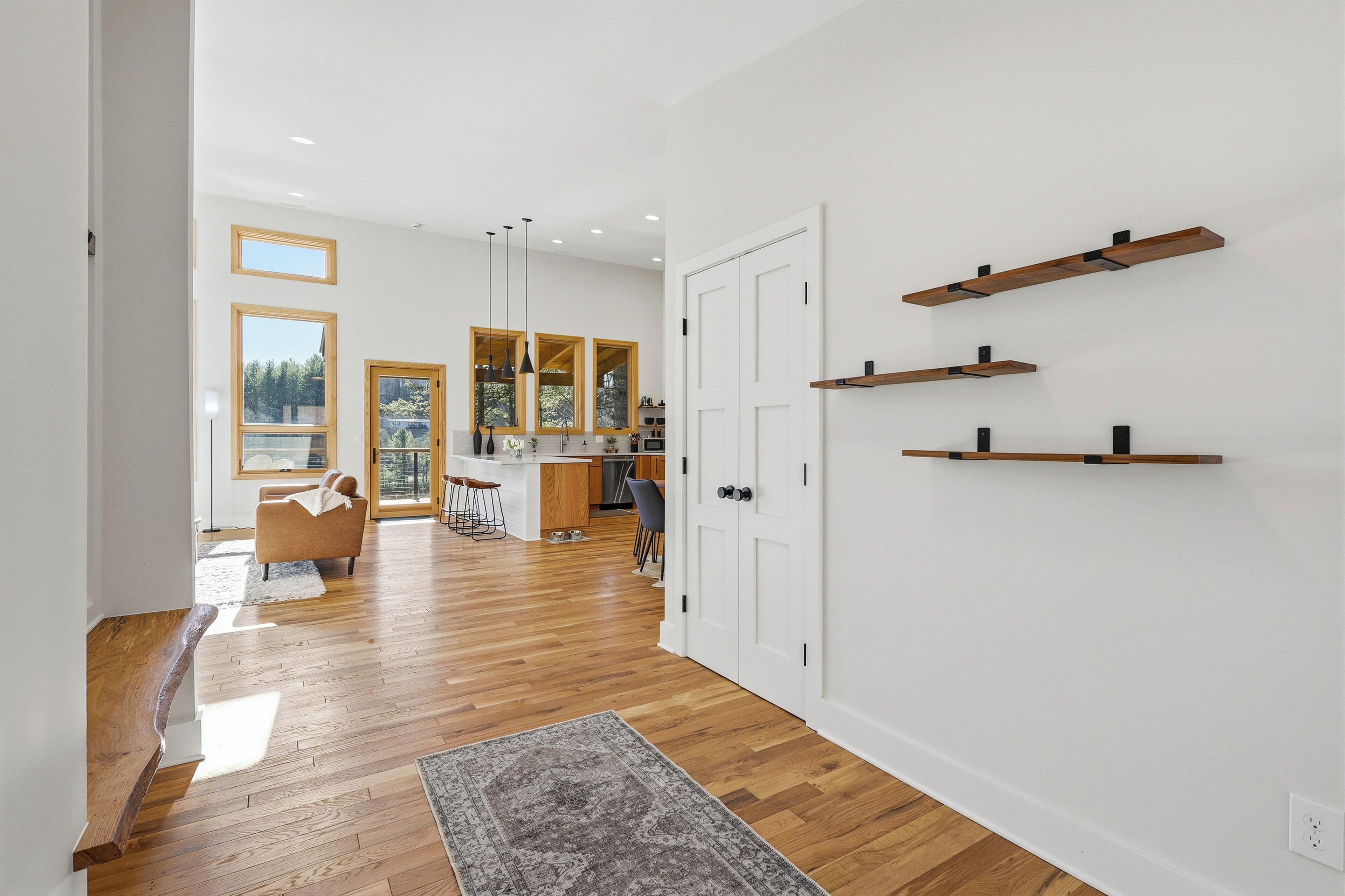 Un intérieur moderne avec un plancher en bois, un coin cuisine et des étagères intégrées.