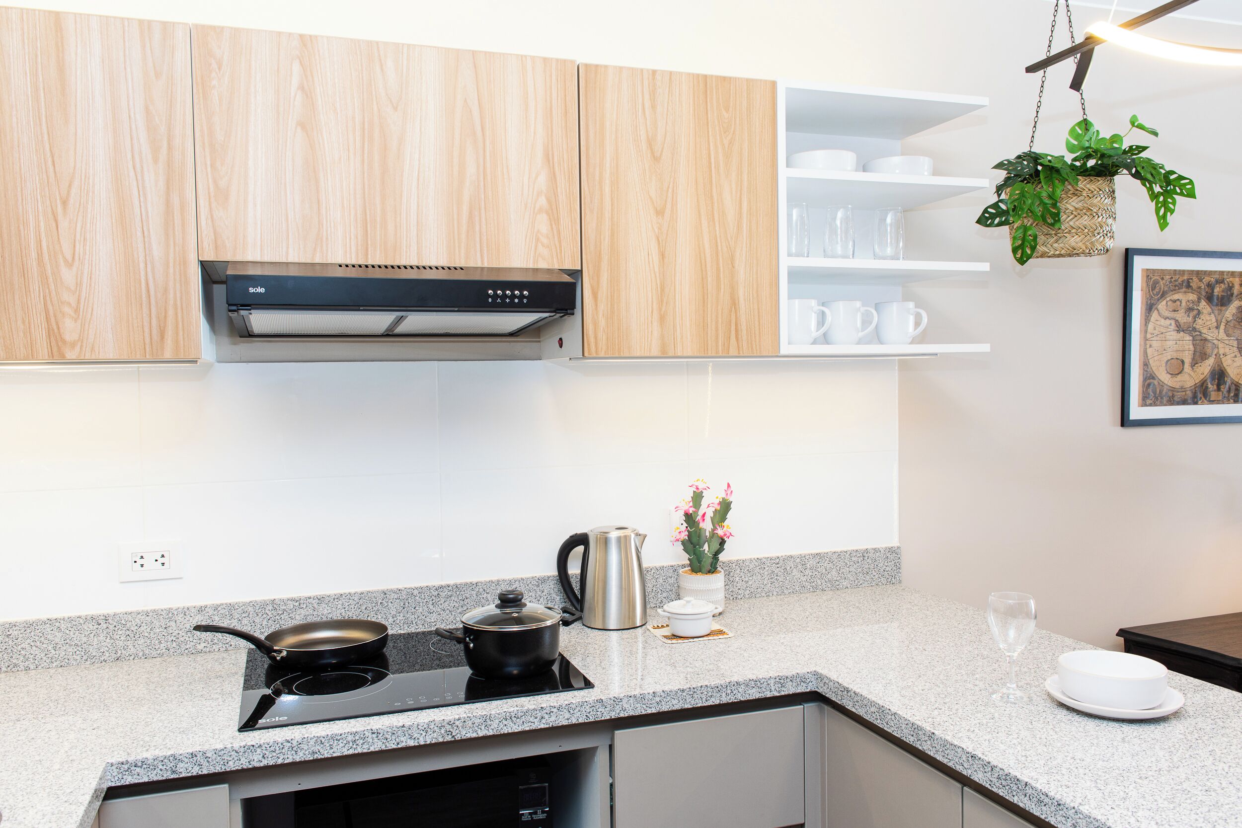 Een moderne keuken met houten kastjes, een inbouwfornuis en een koffiezetapparaat.